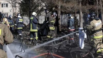 Russian emergency service staff spray water and remove remains at the site of a fire at a psychiatric hospital in the village of Ramensky