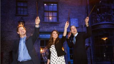 Prince Harry, Catherine, Duchess of Cambridge and Prince William, Duke of Cambridge raise their wands