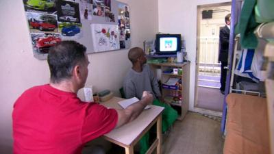 Two prisoners watching television in a cell