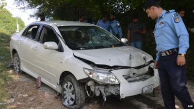 Pakistani police officials examine the bullet-riddled car of Chaudhry Zulfiqar