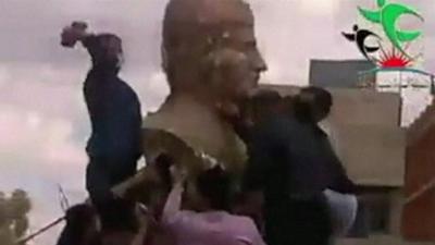 A still from unverified amateur footage apparently shows a statue of Syrian leader Bashar al-Assad's father being attacked