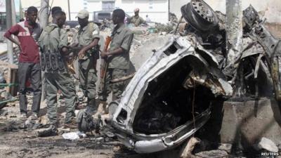 Officers stand by the remains of a wrecked car south of the capital Mogadishu