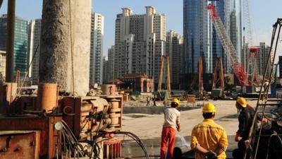 Labourers work at a new property development under construction on the busy Nanjing Road shopping street in Shanghai