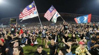 Demonstrators wave flags as they attend a rally in protest of the Sunday's election result