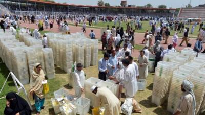 Pakistani election officials receive ballot boxes and other election materials at a distribution centre in Peshawar