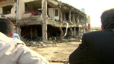 Two men look on at the damage left by two car bombs in the Turkish border town of Reyhanli