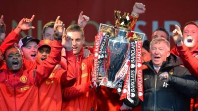 Retiring iconic Manchester United manager Alex Ferguson (R) and his players hold the Premier League trophy outside the town hall in Manchester