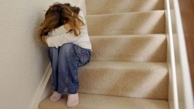 Child on stairs covering face