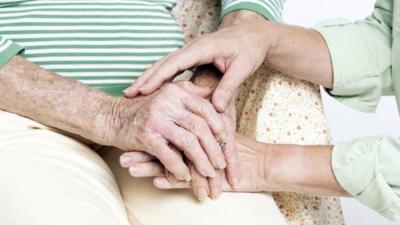 Elderly person's hands with carer