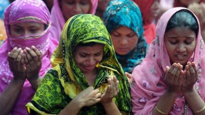 Bangladeshi family members of missing garment workers offer prayers in front of the rubble of a nine-storey building collapse in Savar