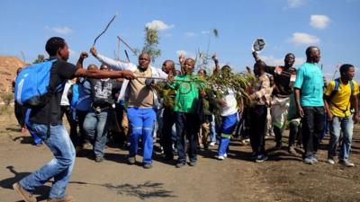 Striking Lonmin mine workers dance and sing while starting to gather next to a hill called Wonderkop