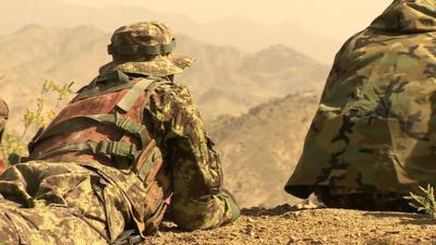 Afghan soldiers look out towards a Taliban base