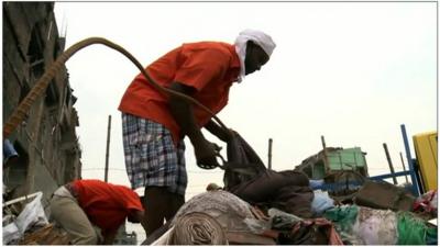 A garment workers seek to recover cloth from collapsed building