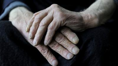 Elderly man rubbing his hands together