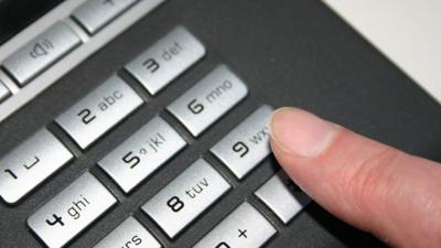 A person about to dial 9 on a telephone