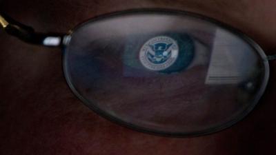 Logo of US Homeland Security office reflected in glasses