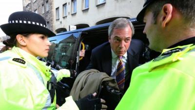 Nigel Farage is escorted by police as he exits a taxi as its path was blocked by protesters as he leaves the Cannons Gait pub during his visit to Edinburgh