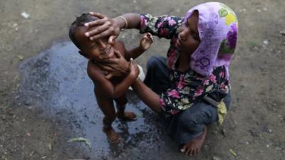 A woman, from Rohingya internally displaced persons (IDP) camp, bathes her son in a school where she and others were evacuated to shelter from cyclone Mahasen when it landed,