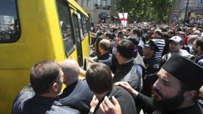 Anti-gay protesters try to attack a bus with gay activists who are being taken to safety by police from a rally in Tbilisi, Georgia