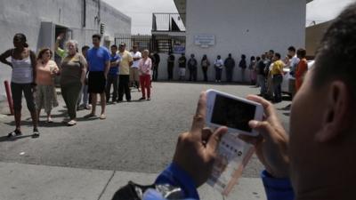 A man takes pictures of people queuing to buy Powerball tickets outside Bluebird liquor store in Hawthorne, California