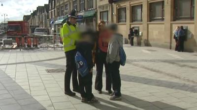 Police and education officer stop and talk to two boys