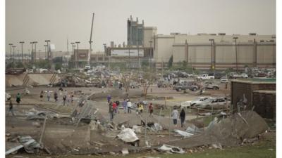 People walk through a damaged area near the Warren Theatre after a powerful tornado ripped through Moore