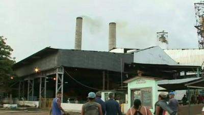 Workers walk into the sugar mill