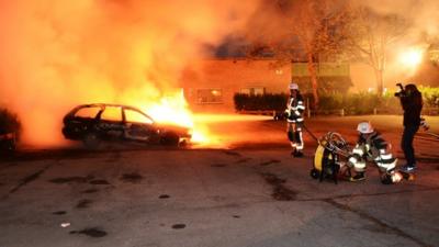 Swedish fire-fighters attempt to put out a car that is ablaze