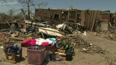 A pile of salvaged beongings outside a damaged house