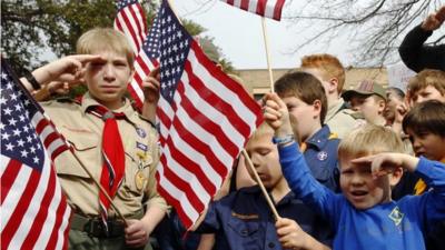 Joshua Kusterer, 12, Nach Mitschke, 6, and Wyatt Mitschke, 4, salute as they recite the pledge of allegiance during the “Save Our Scouts