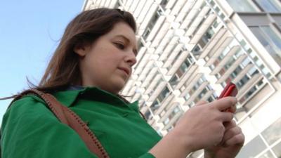 Woman watching tv on her mobile phone on the street