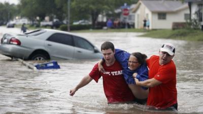 Marco Fairchild, left, and Gary Garza, right, help Sueann Schaller from her car Saturday, May 25, 2013 in San Antonio after she drove it into floodwaters