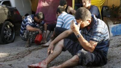 Injured men are treated by friends after the rocket attack in Beirut, 26 May