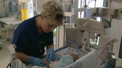 Nurse treating baby in neonatal unit