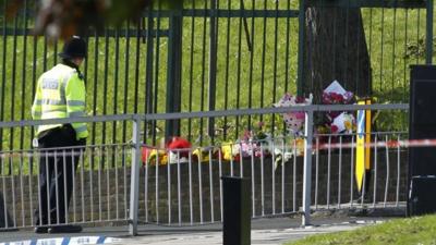 A police officer looks at floral tributes as he guards the scene of a terror attack in Woolwich