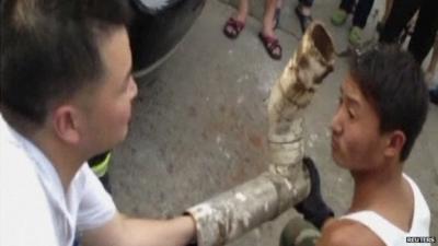 Chinese firefighters try to reach a trapped baby inside a sewage pipe