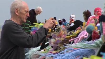 Man taking pictures of knitted figures in Saltburn