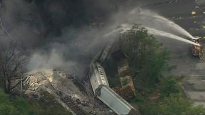 Firefighters pouring water on derailed carriages