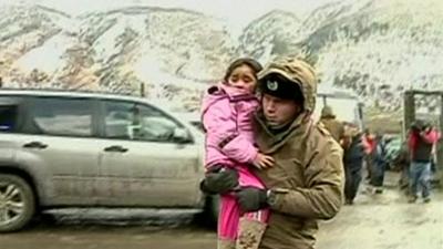 A soldier carries a girl to a truck