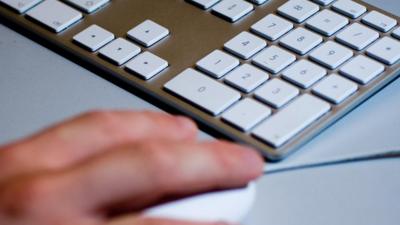 A person using a computer mouse and keyboard