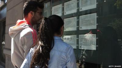 Two people look at job announcements on the window of an agency in Naples