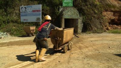 Man pushing cart outside gold mine in Ecuador