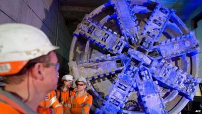 Crossrail construction workers stand near to one of the 1,000 tonne tunnel boring machines to mark the breakthrough into the Canary Wharf station