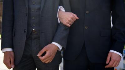 In a file picture taken on June 3, 2013 men link arms outside the Houses of Parliament in central London during a rally in support of same-sex marriage.