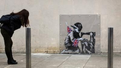 Woman looking at Banksy mural