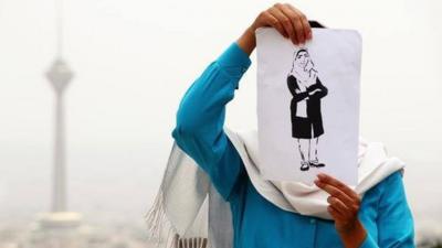 A woman holding a drawing of Zahra
