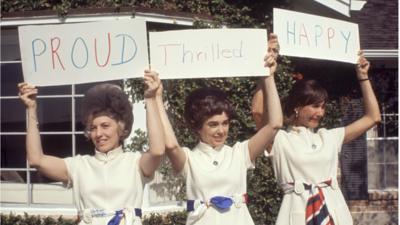 Astronauts' wives hold up signs