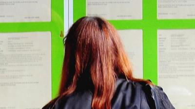 Woman looking into the window of a Job Centre