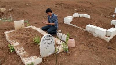 A man prays at the grave of a Free Syrian Army fighter at a cemetery at al-Karak al-Sharqi in Deraa