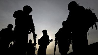 US soldiers belonging to the NATO-led International Security Assistance Force (ISAF) are silhouetted as they walk during a patrol outside Bagram airbase